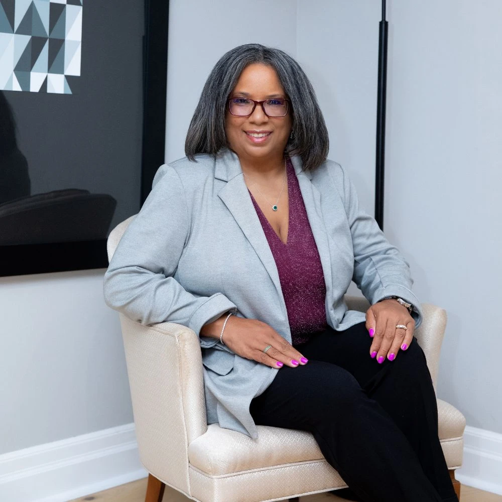Professional woman in gray blazer seated in elegant chair