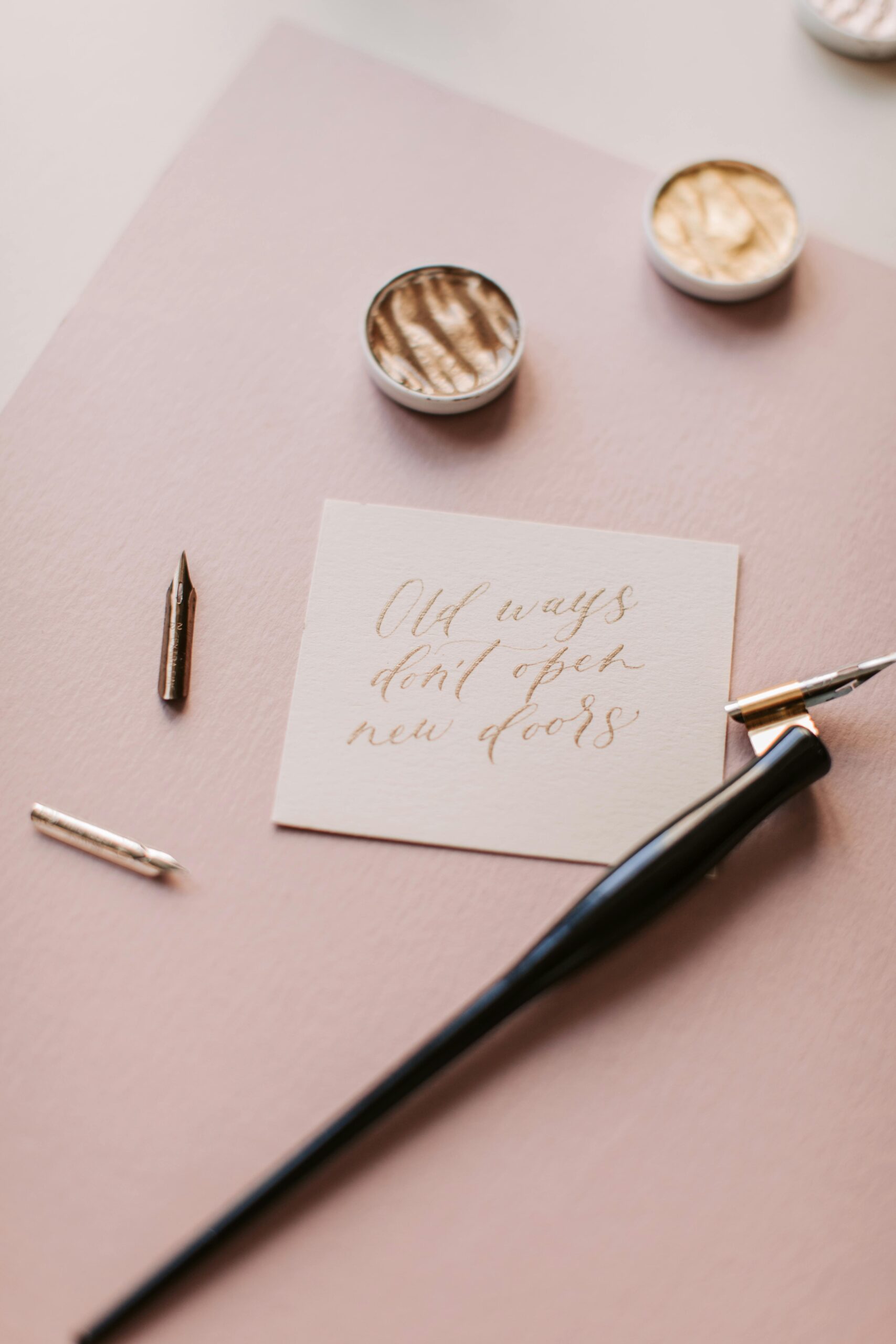 Artistic calligraphy on a note with a pen and ink, set against a pastel backdrop.