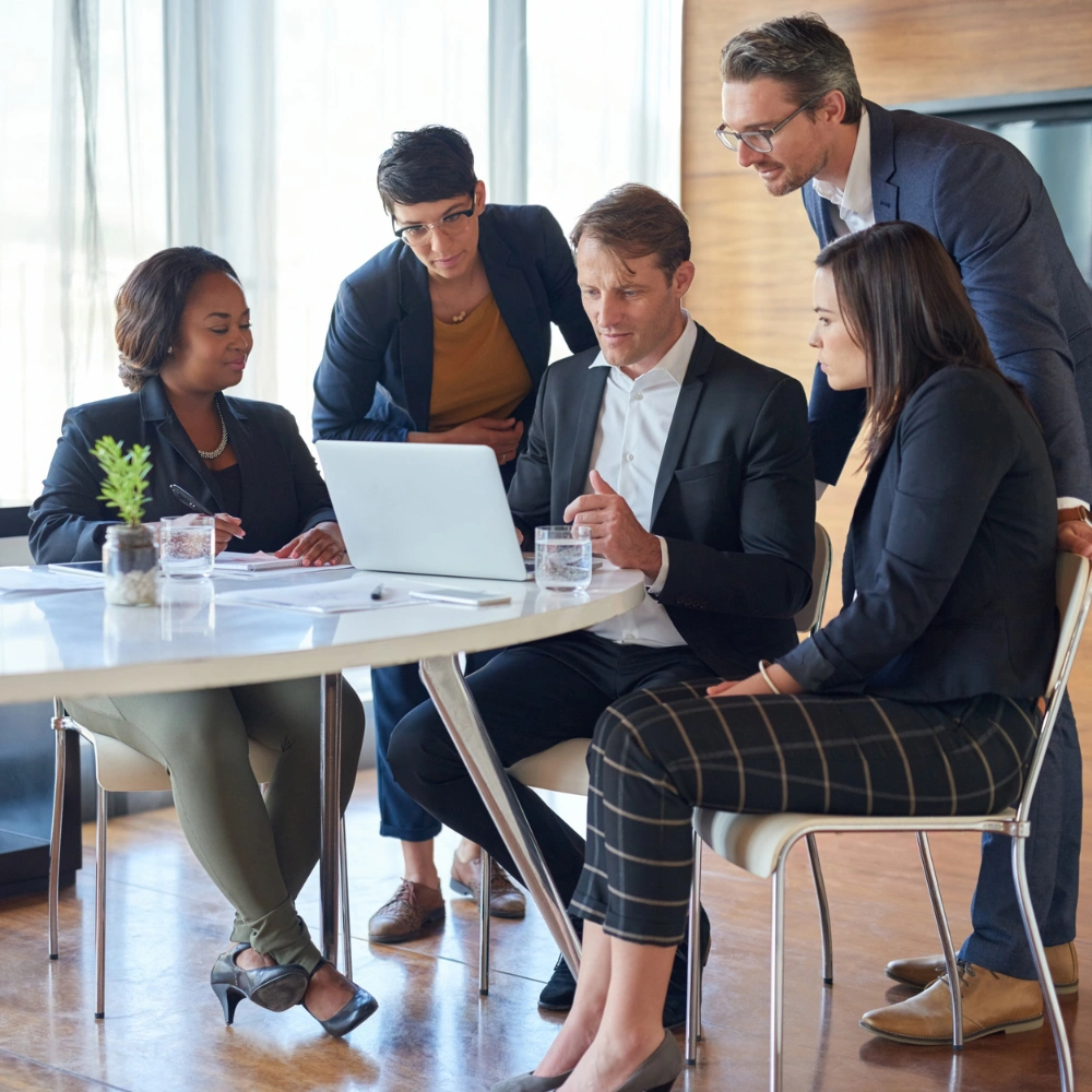 Five business professionals collaborating around laptop in office